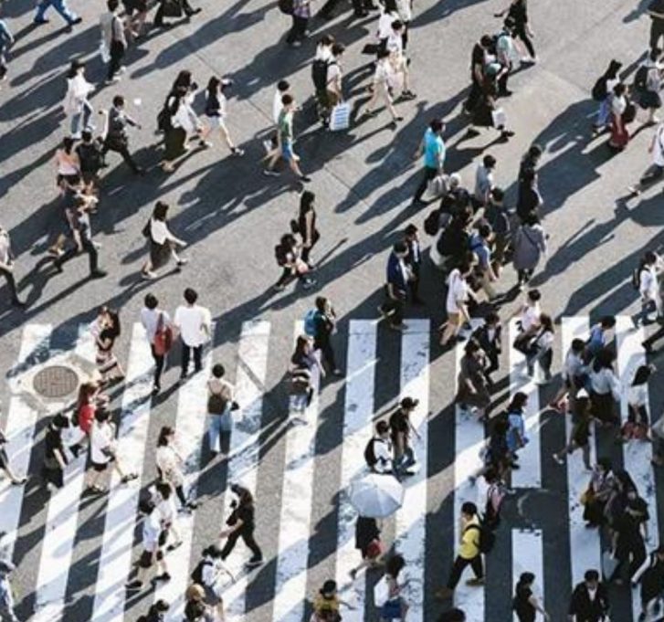 lots of people walking across a busy zebra crossing